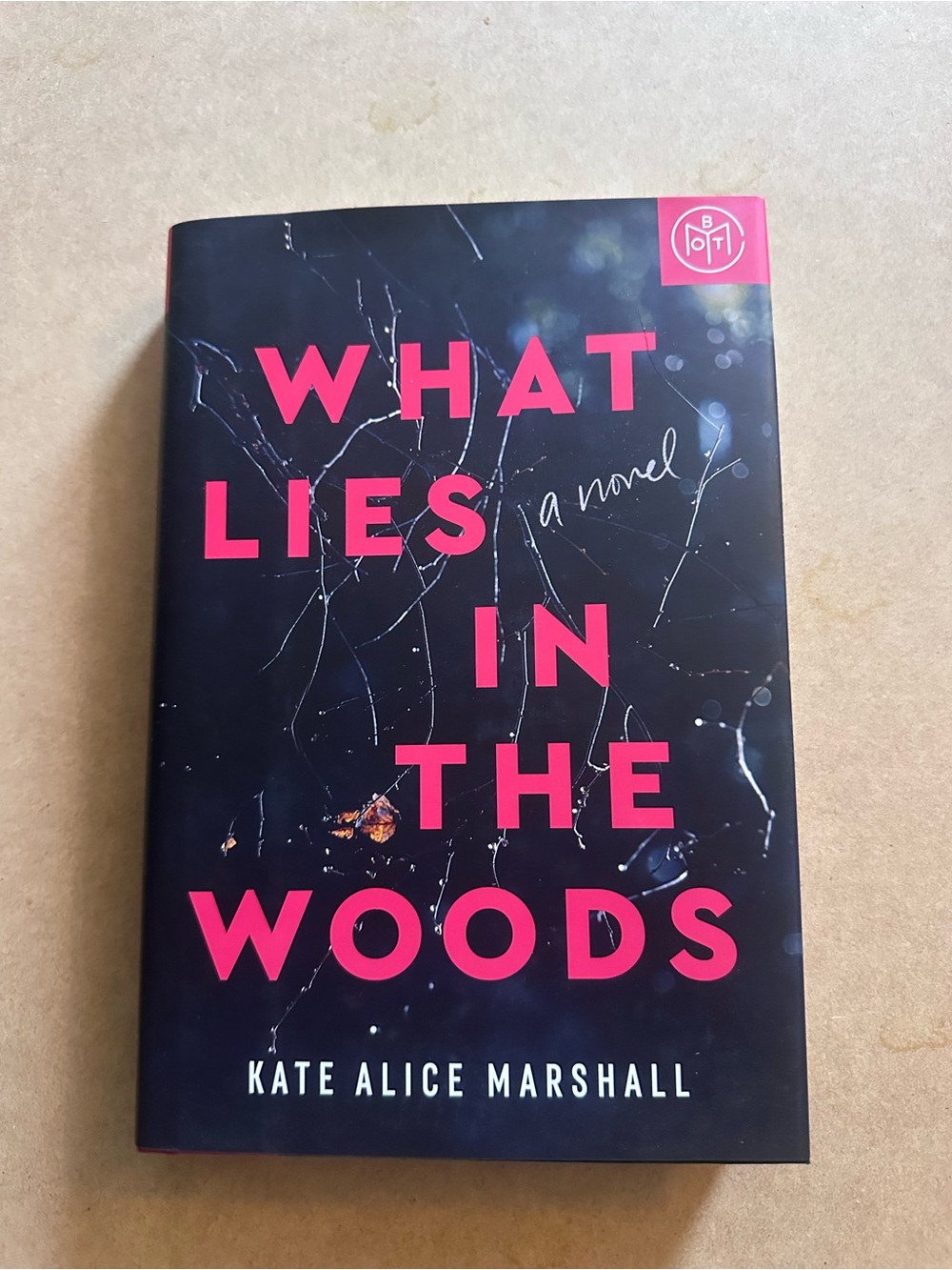 "What Lies in the Woods" Hardcover Novel - Black with Pink Text